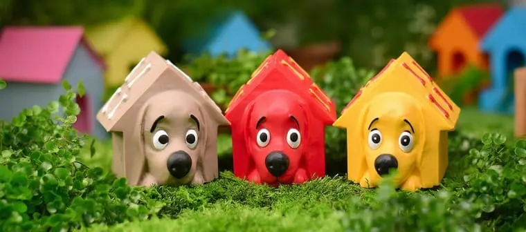 Brinquedos de vinil em formato de casinha com rosto de cachorro, nas cores bege, vermelha e amarela